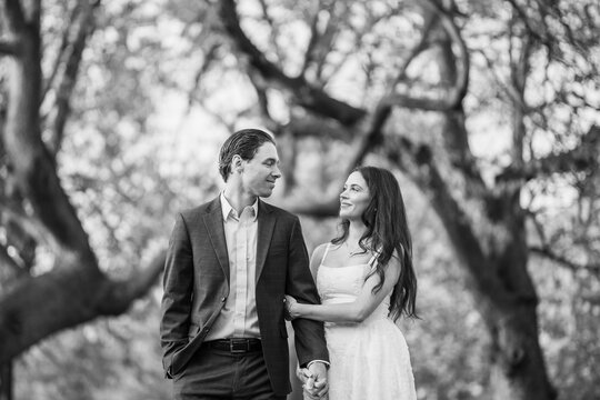 Young couple holding hands in park looking at each other