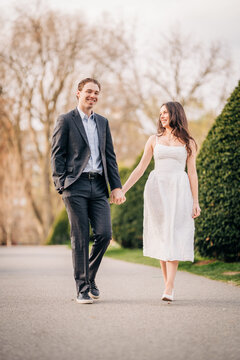 Happy young couple holding hands walking park path