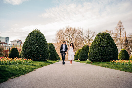 Happy couple walking hand in hand through a park