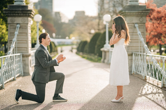 Man on one knee proposing to woman in park