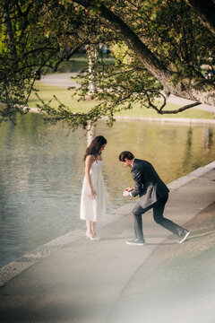 Man proposing marriage to woman by a lake in the park