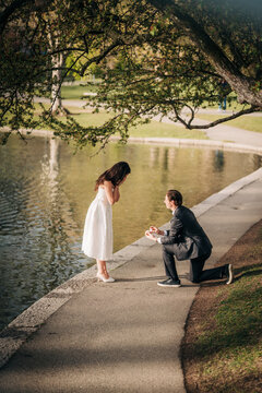 Man on one knee proposing to surprised woman in a park