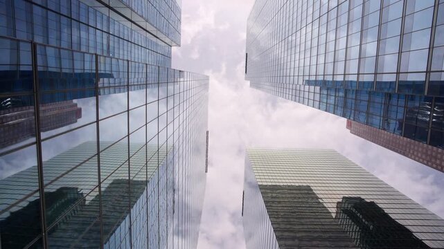Camera moves forward while looking upward between glass office towers in Toronto financial district with fast moving clouds, Hyperlapse