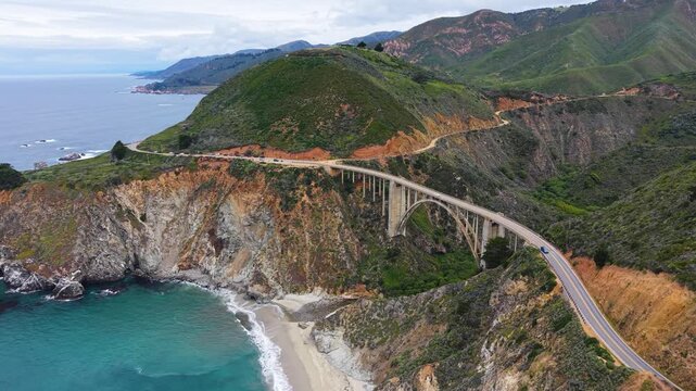 Aerial drone view of the iconic Bixby Creek Bridge arching over a canyon along Big Sur's Highway 1.