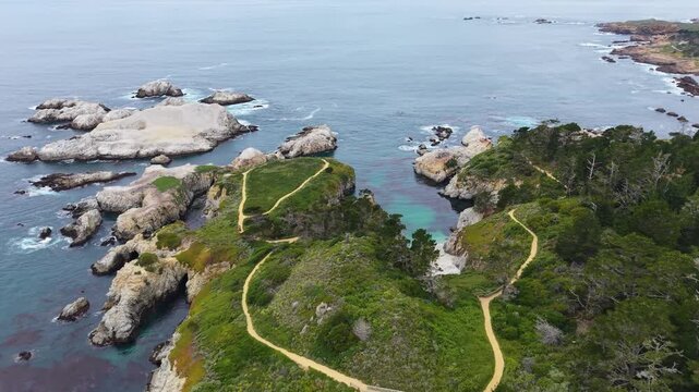 Aerial drone view of granite rock formations hiking trails and turquoise coves at Point Lobos in California.