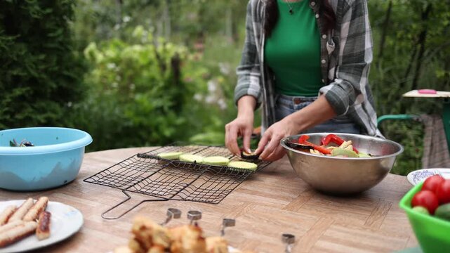 Woman preparing sliced zucchini for grilling in backyard garden