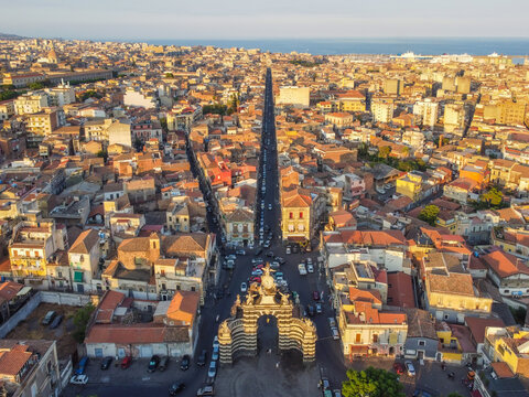 Aerial view of the historic Porta Garibaldi archway and the surrounding dense urban landscape with terracotta rooftops and narrow streets in Catania, Sicily, Italy.