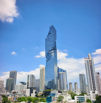Modern skyscraper mahanakhon tower rises above the city skyline under a blue sky with white clouds in Thai capital Bangkok