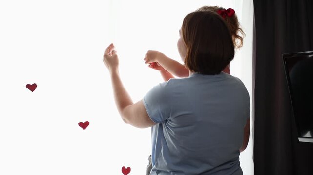 Caucasian mother embracing her young daughter and giving a gentle kiss in a cozy home setting. Family affection and child protection concept. Warm parenting and unconditional love. Back view
