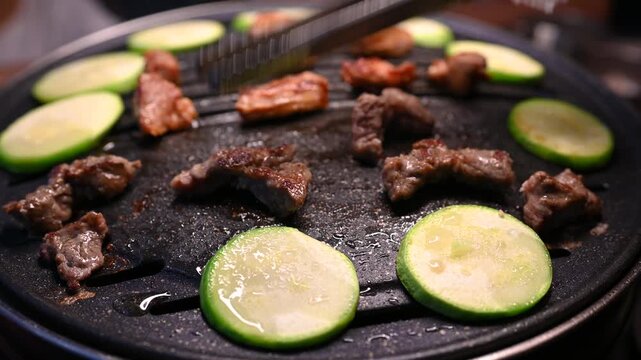 Grilled Meat and Sliced Cucumbers on a Hot Plate in a Restaurant Setting