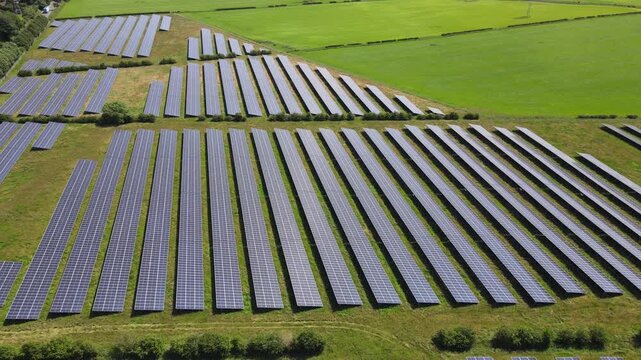 4K drone footage tracking over multiple rows of solar panels on a summer day in the UK