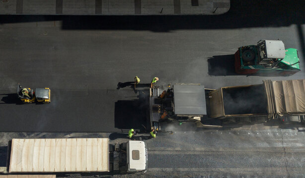 Workers laying of asphalt over parking area lot