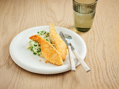 Breaded fish fillet with herb rice and green peas, casual dining experience, family-friendly meal idea