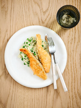 Breaded fish fillet served with creamy risotto and peas, fine dining menu, seafood experience
