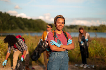 Fototapeta premium Group of volunteers cleaning up polluting garbage near lake