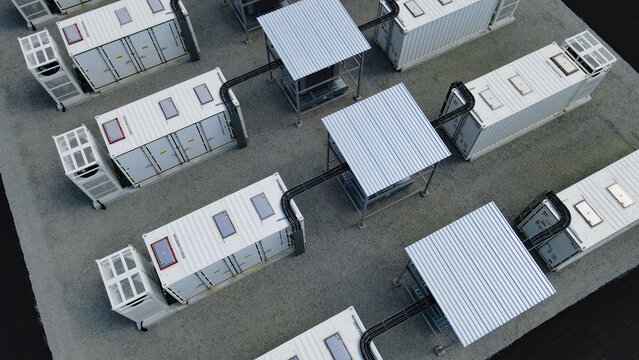 Aerial view showing multiple large battery energy storage system - BESS - containers connected to central transformer units, forming a park for utility scale clean energy storage and power management