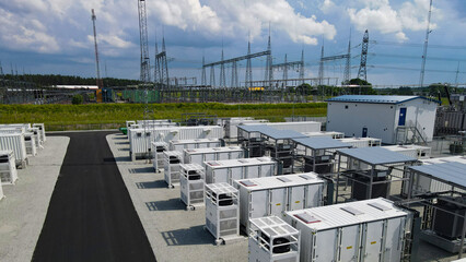 Battery energy storage system containers and an electrical substation connect power to the energy grid, representing modern infrastructure for managing renewable electricity © Dark Artistic