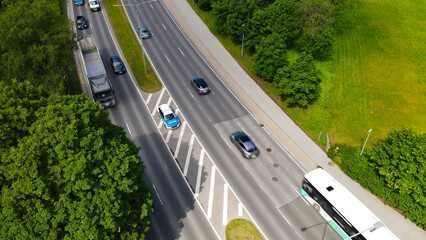 Estonian police car standing on a median strip, monitoring vehicles and enforcing speed limits on a multi lane urban road with cars, a bus, and surrounded by green trees © Dark Artistic
