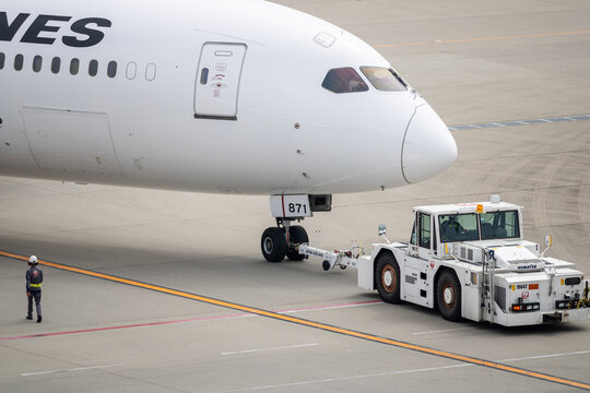 Tokyo, Japan April 13, 2026 exterior view of the front section of a japan airlines passenger aircraft as it is being towed on the airport apron by a pushback tug. 