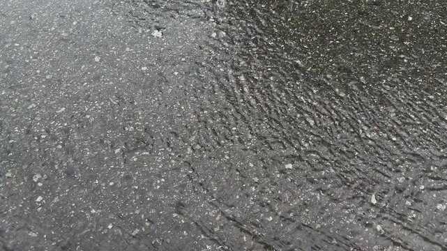 Rainwater Runoff and Raindrops Flowing on Wet Gray Asphalt Copy Space Background