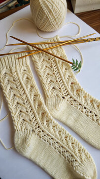 Hand-knitted socks with a ball of yarn nearby; handmade.