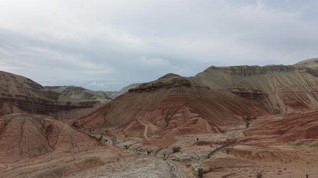 Aerial drone footage of the colorful Aktau Mountains in Altyn Emel National Park, Kazakhstan. Dramatic desert landscape with striped clay hills, rocky formations and scenic travel destination atmosphe