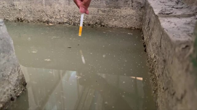 pH test strip submerged in wastewater during routine analysis. Environmental testing for water safety, treatment efficiency, and compliance.