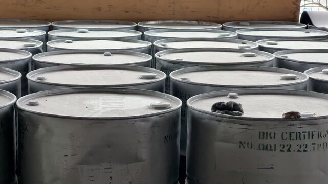 Large collection of sealed chemical barrels arranged in an industrial storage area. Chemical inventory, warehouse management, and hazardous material handling concept.