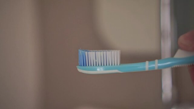 toothpaste being applied to a toothbrush. Daily oral hygiene routine in a bathroom setting, promoting dental care, fresh breath, and healthy teeth