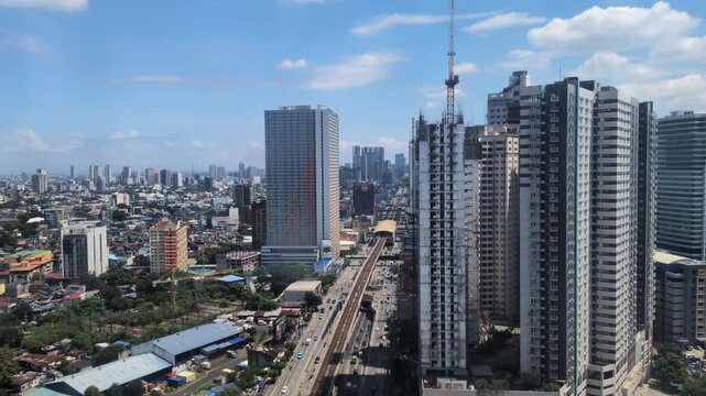 Wide static shot of high-rise buildings and condominium towers along EDSA highway in Quezon City with traffic and urban development - Philippines
