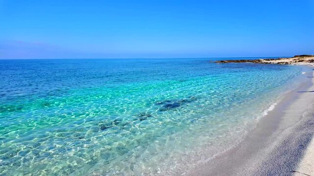 Is Arutas beach in Sardinia, Italy. Beautiful tropical-like coast with unique quartz white sand, crystal clear turquoise water and rocky shoreline under a clear blue sky