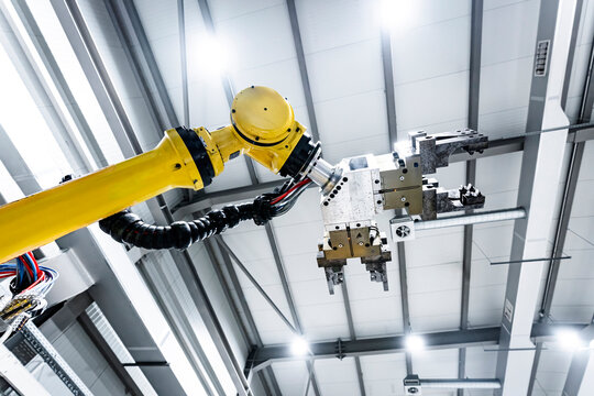 Yellow robotic arm with machine under ceiling in factory
