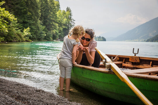 Austria, Carinthia, Weissensee, mother in rowing boat with daughter at the lakeside