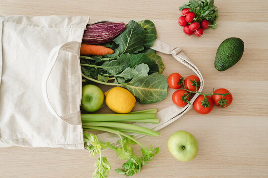Fresh organic vegetables and fruits in reusable bag on table