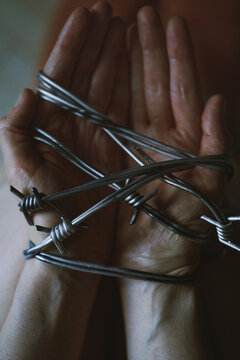 Hands bound with barbed wire representing captivity and pain