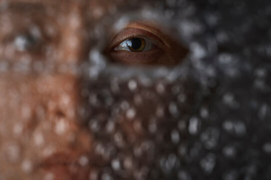 Eye looking through hole in bubble wrap showing isolation