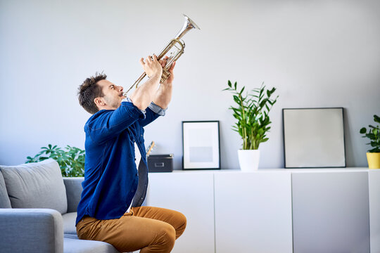 Man sitting on couch playing trumpet