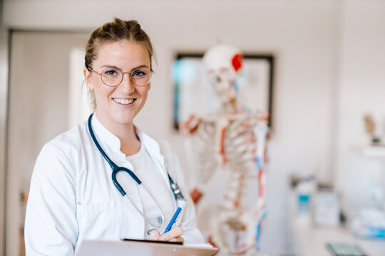 Portrait of smiling female doctor with anatomical skeleton in the background