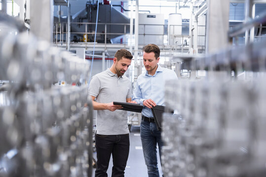 Two men with tablet talking in factory shop floor