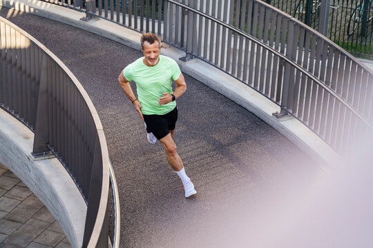Active sportsman jogging on footbridge
