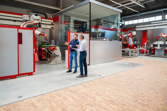 Team discussing automation near industrial robot in factory