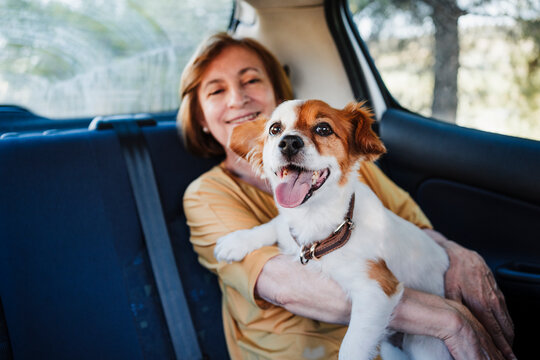 Senior woman with dog sitting in car
