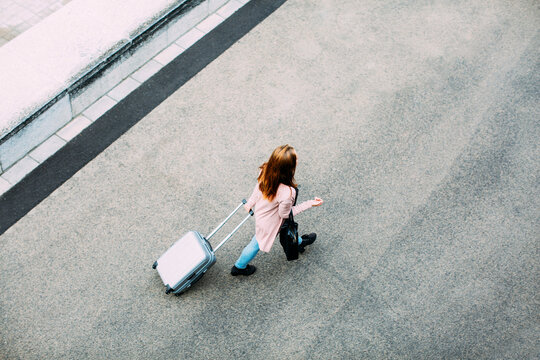 Top view of walking woman with wheeled luggage