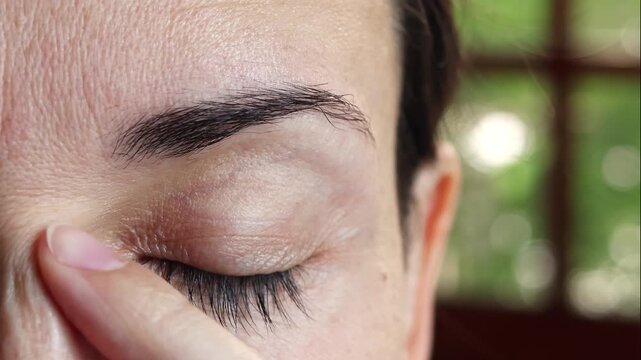 Middle Aged Woman Performing Gentle Eye Area Massage for Skin Care and Wrinkle Prevention. Close-Up Real Time Footage of Beauty Routine.