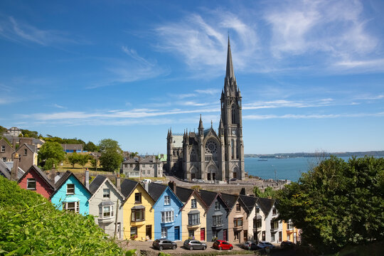 Ireland, County Cork, Cobh, Colorful row houses standing along steep street with Saint Colmans Cathedral in background