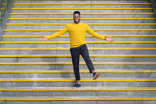 Smiling man with arms outstretched standing on staircase