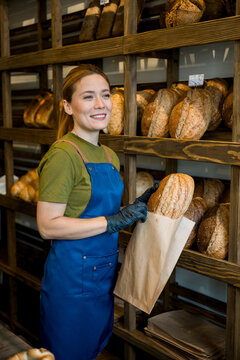 Shop assistant working in a bakery selling fresh bread with a smile