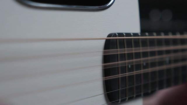 Slow Motion Close Up of Thumb Strumming Acoustic Guitar Strings