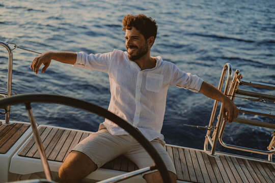 Sailor relaxing on a sailboat deck during summer vacation at sunset