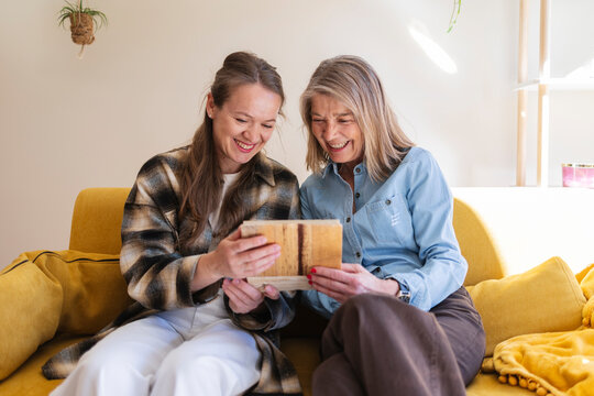 Mother and daughter sharing a happy memory on a sofa indoors
